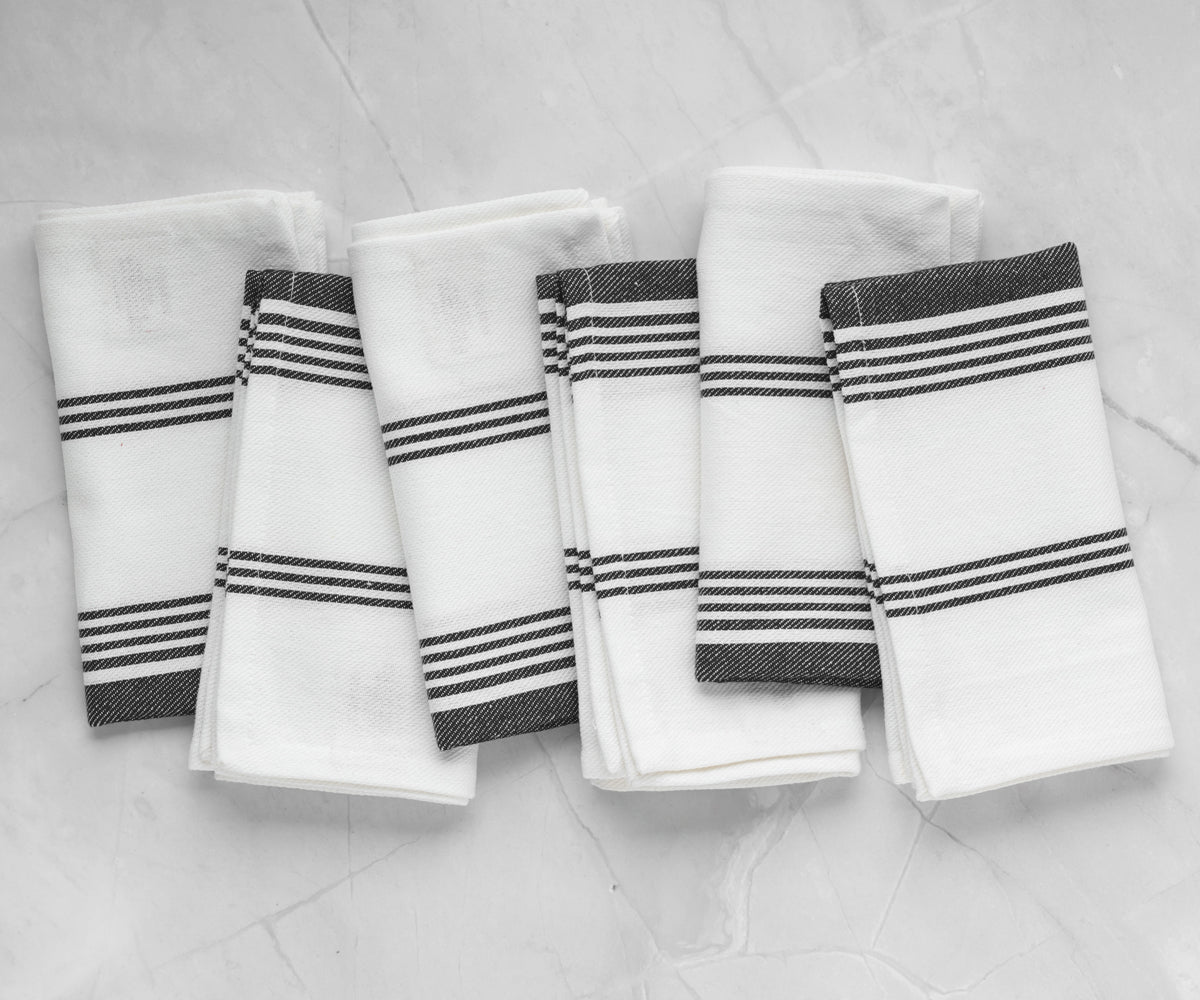 A set of four black striped napkins neatly arranged on a marble countertop