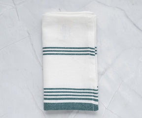 Green and white napkins with a subtle pattern, blending well with rustic table settings.