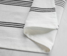 One black striped napkin laid out on a marble background