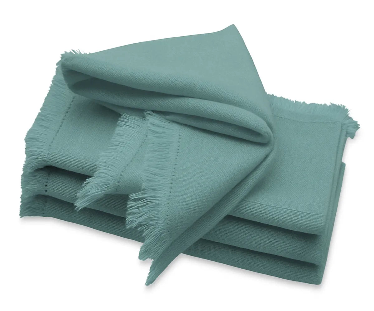 Turquoise cotton napkins with frayed edges, stacked neatly on a dining table