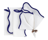 navy blue linen scalloped napkins neatly folded on a dinner table with white plates and gold flatware.