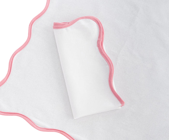 Elegant peony pink linen scalloped napkins placed on gold-rimmed plates for a classy dinner setup.