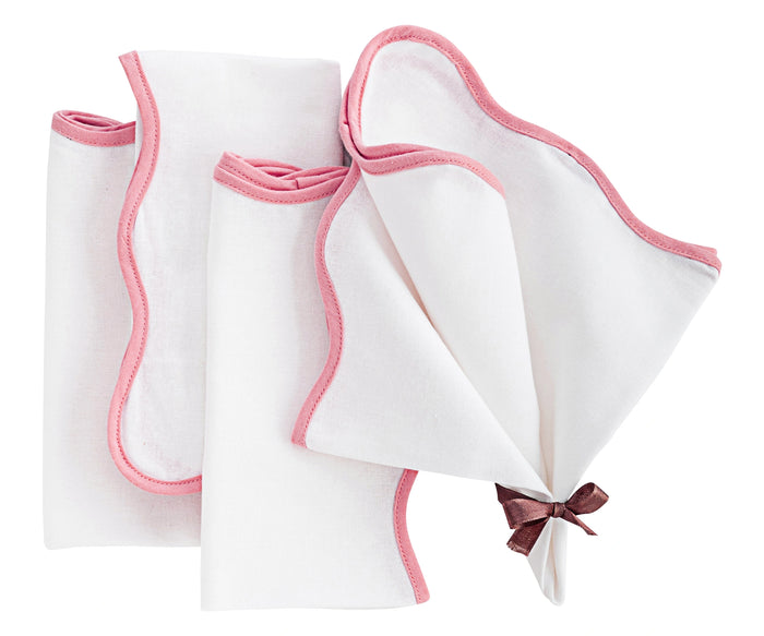 peony pink linen scalloped napkins neatly folded on a wedding table with floral decorations.