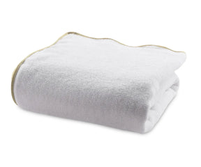 Folded white cotton bath towel with beige edge showing plush, thick texture