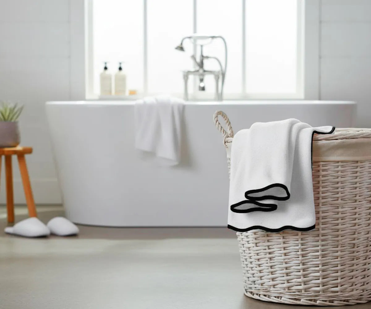 Soft and durable white towel with a chic black trim, offering high absorbency and timeless style — perfect for adding elegance to any bath collection.