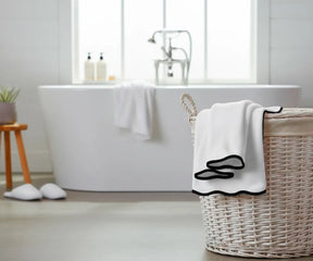 Soft and durable white towel with a chic black trim, offering high absorbency and timeless style — perfect for adding elegance to any bath collection.