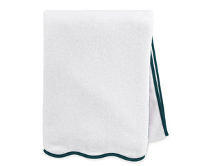 White bath towel with green border hanging on a rack in a modern bathroom