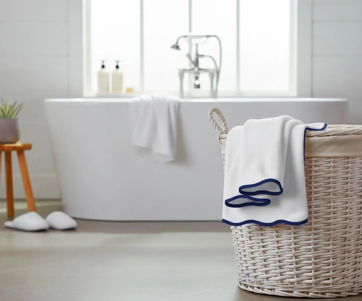 White bath towel with navy edge hanging on a modern bathroom rack
