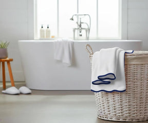 White bath towel with navy edge hanging on a modern bathroom rack