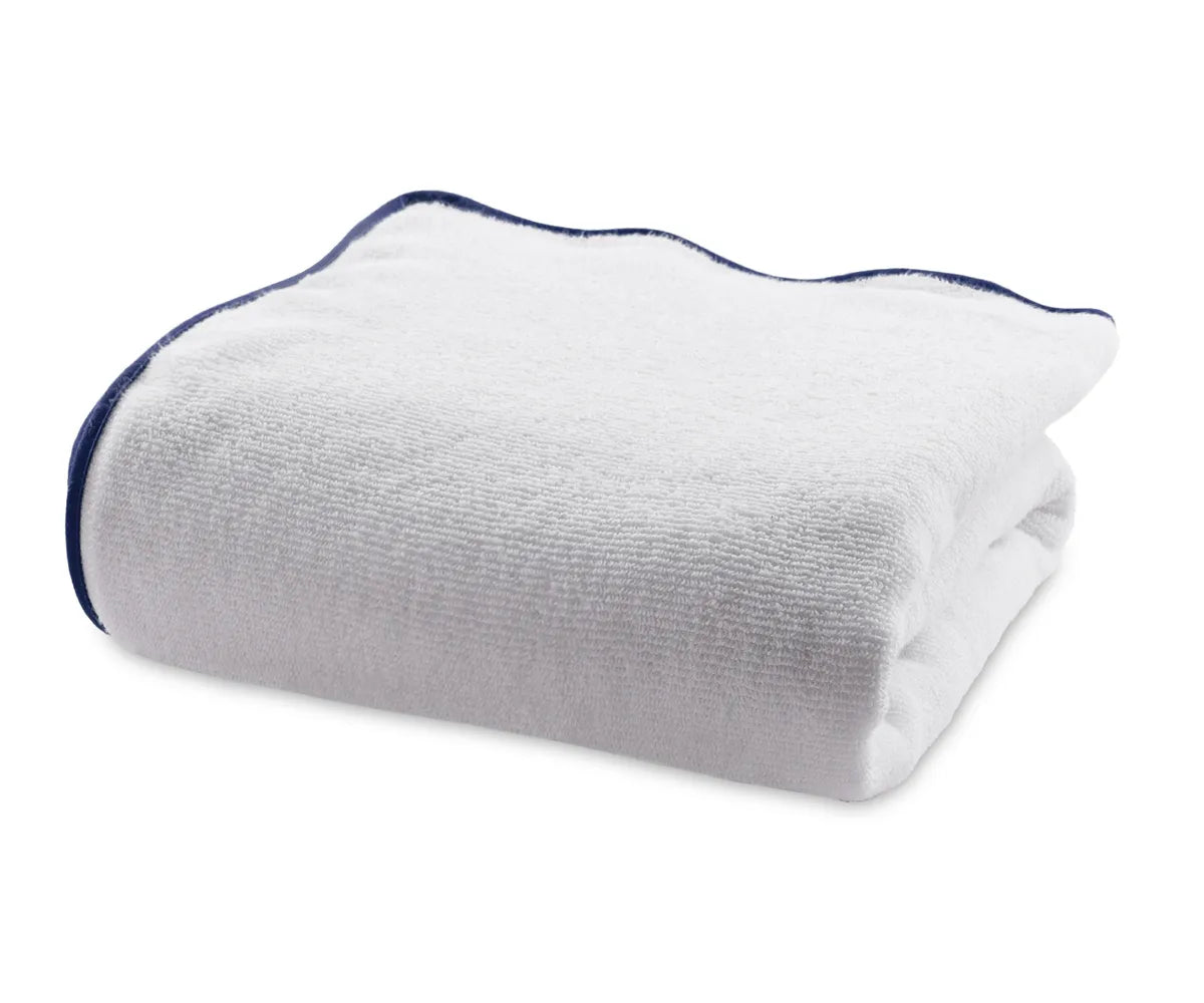 Folded white cotton bath towel with navy blue border showing soft, thick texture