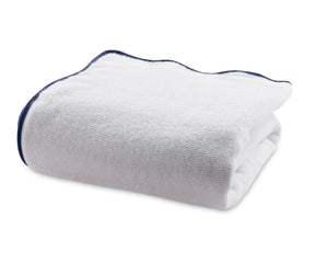 Folded white cotton bath towel with navy blue border showing soft, thick texture