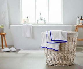 Stack of thick white cotton towels with royal blue trim, ideal for bathroom or spa use