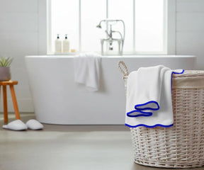 White bath towel with royal blue edge hanging on a bathroom rack