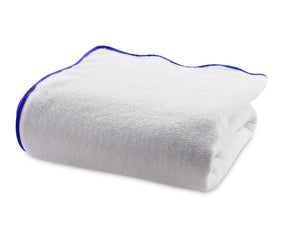 Folded white cotton bath towel with royal blue border showing thick, soft texture