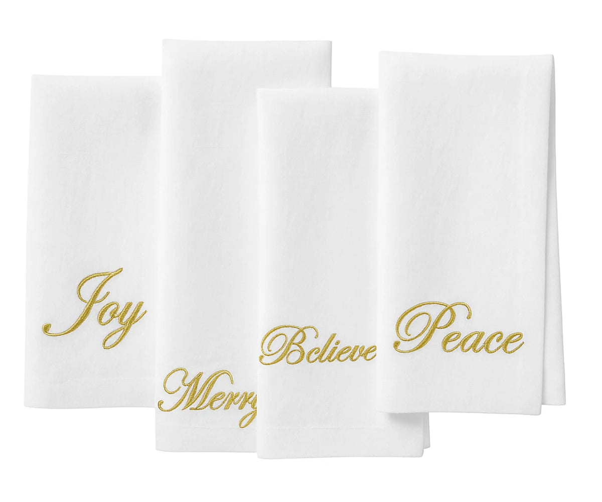 White napkins with gold text 'Joy', 'Believe', 'Peace' on a white background