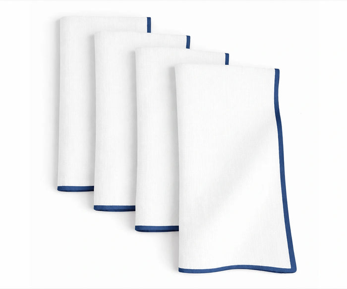 Crisp white cotton napkins featuring royal blue merrow stitched edges for vibrant dining presentations
