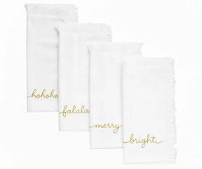 White Christmas embroidered napkins with gold lettering and fringed edges for elegant table settings