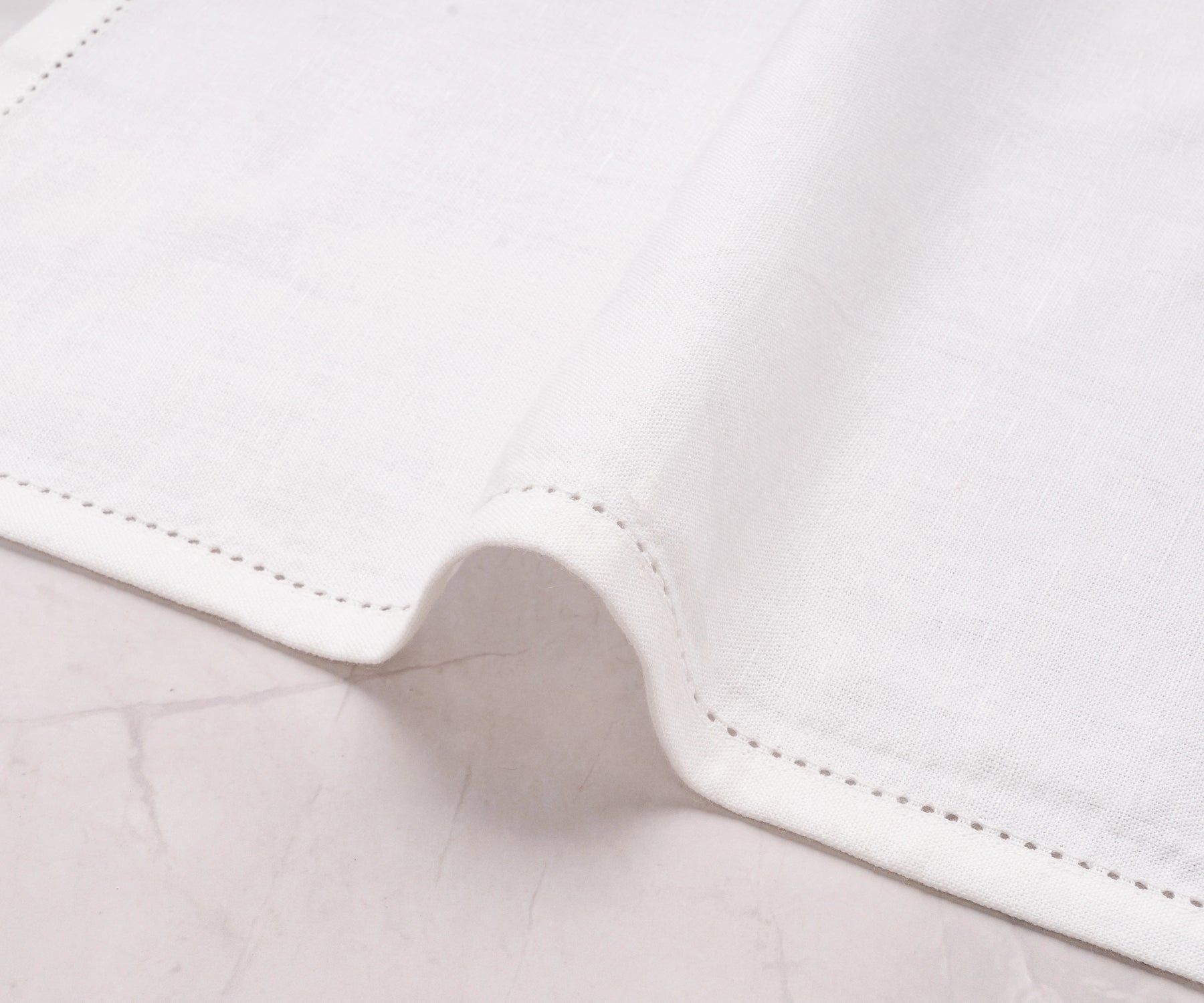 Single white cotton-linen blend napkin folded elegantly to show hemstitched edge