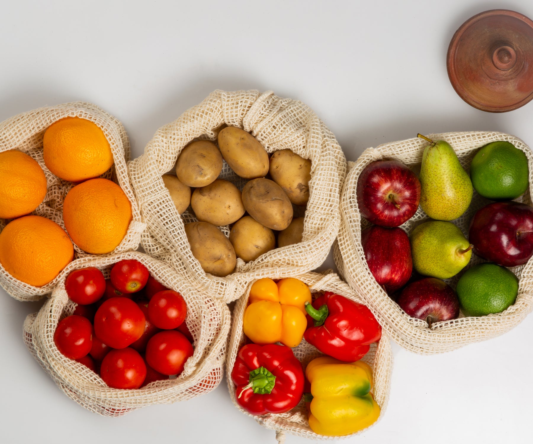 Multiple string bags filled with a colorful variety of fruits and vegetables