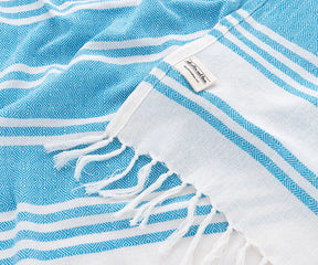 Lightweight striped aqua beach towels paired with sun hats and lounge chairs
