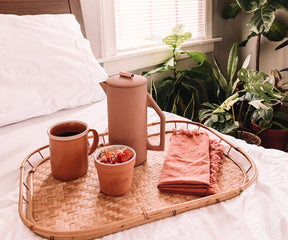 Bed with a cotton fitted sheet and a tray with coffee pot and mug