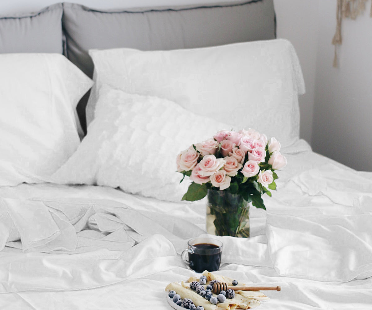 Cotton fitted sheet set displayed on a bed with a vase of flowers and breakfast tray