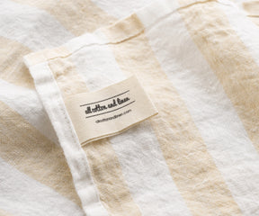 Beige striped linen towel with cotton label detail and natural fabric texture italian linen towels