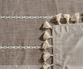 Textile with decorative tassels and braided patterns on a brown fabric background