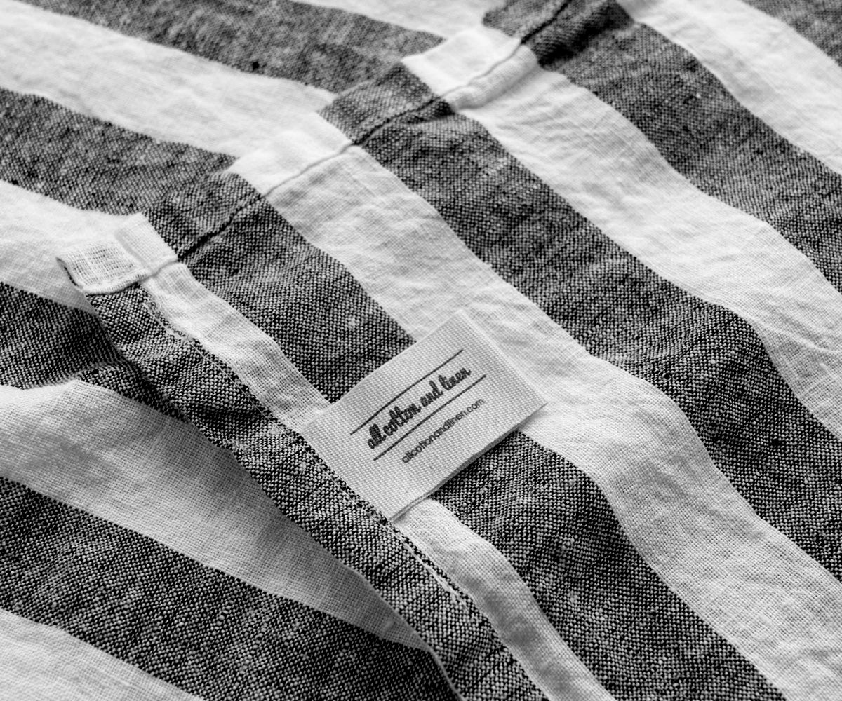 Black and white striped linen towel with brand label detail and textured weave