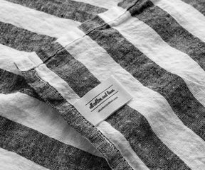 Black and white striped linen towel with brand label detail and textured weave
