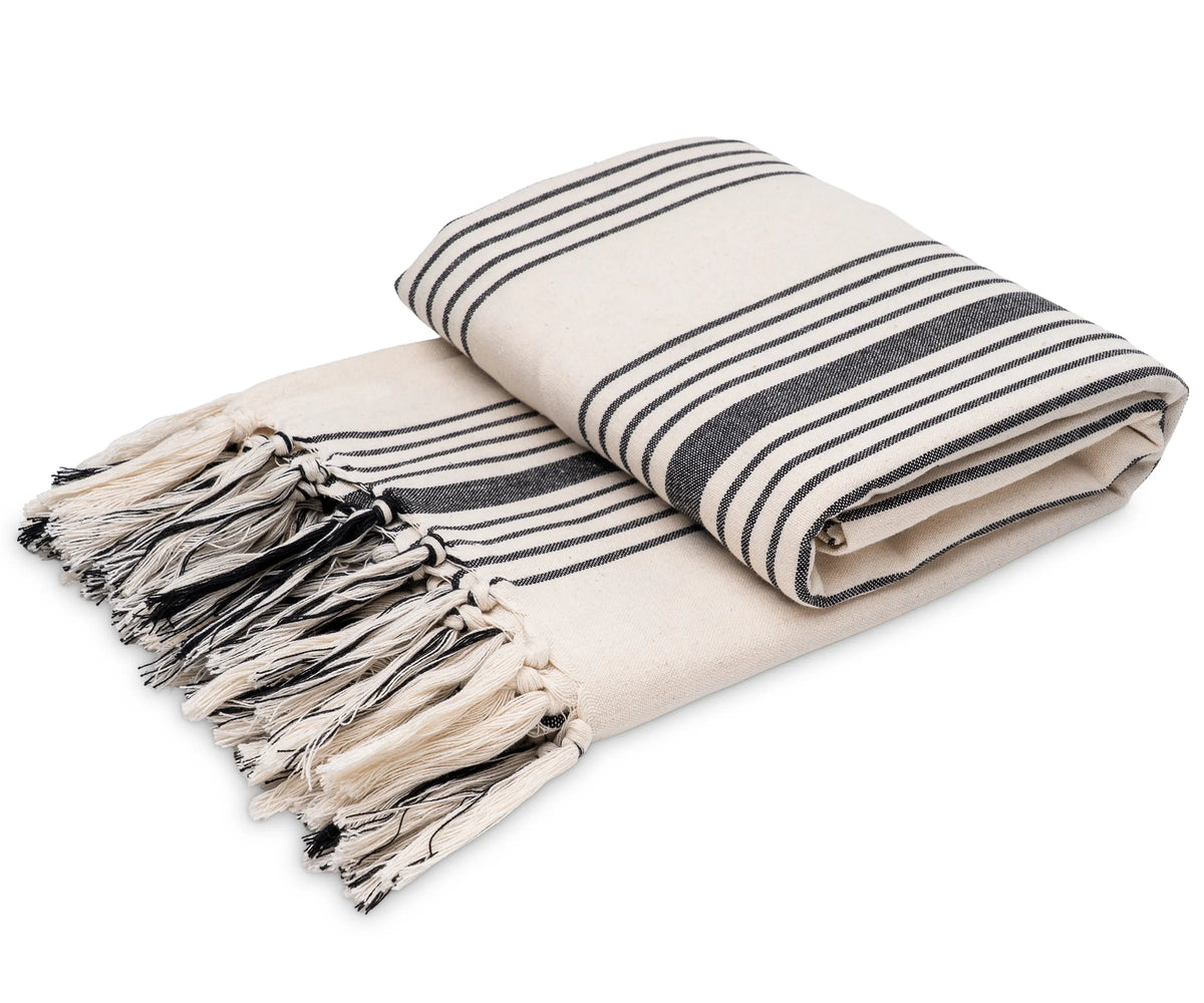 Black and white striped cotton throw blanket with tassel fringe, styled on a sofa for everyday home décor