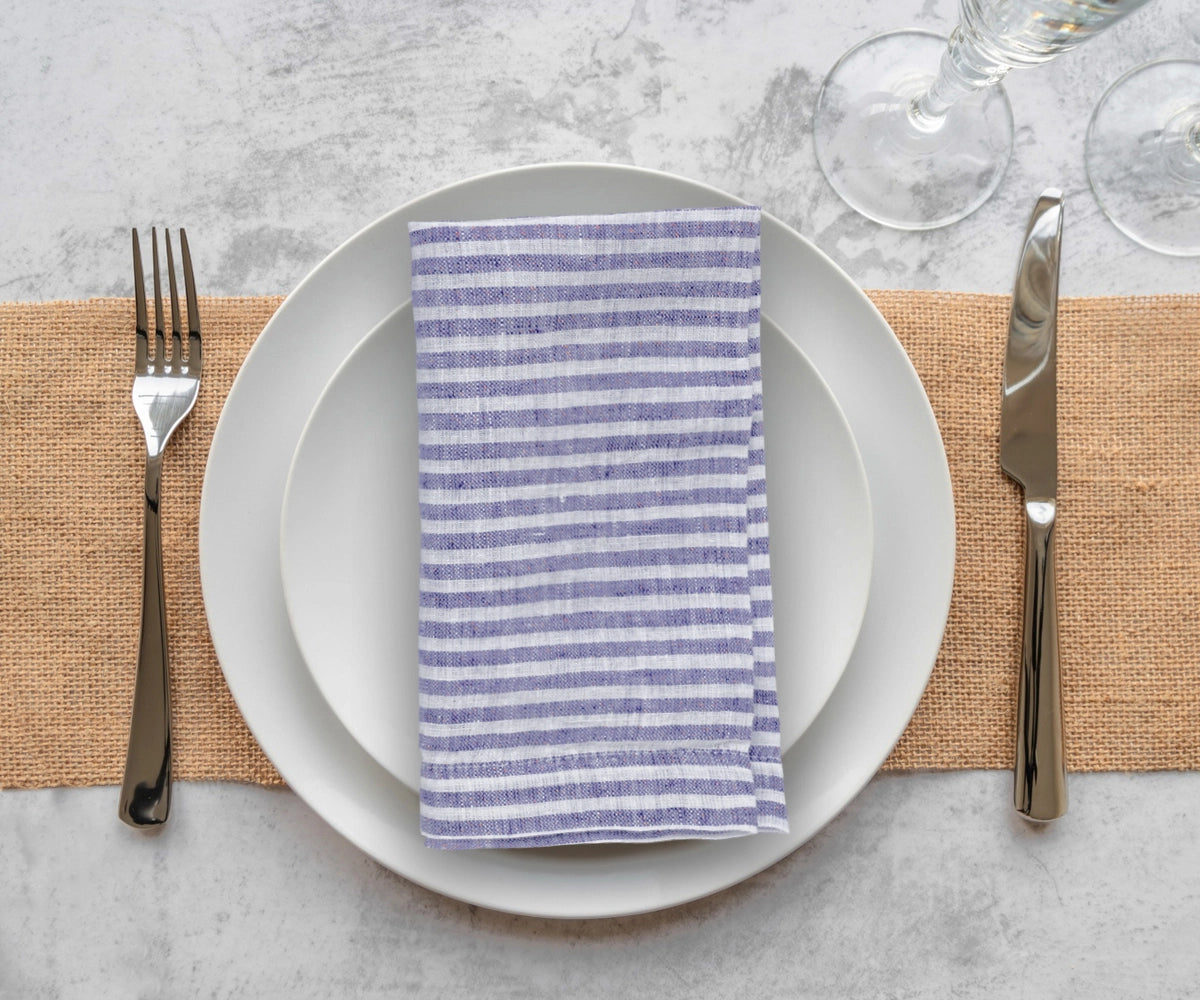 Blue and white pinstripe linen napkins arranged on reception tables for classic wedding décor inspiration