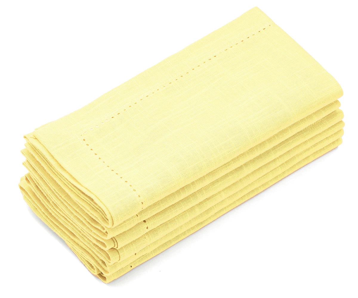 Set of 12 butter yellow hemstitched napkins stacked on a white surface