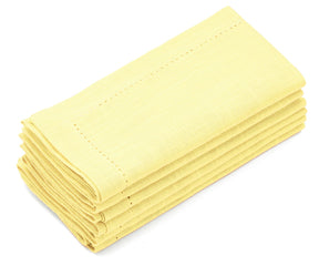 Set of 12 butter yellow hemstitched napkins stacked on a white surface