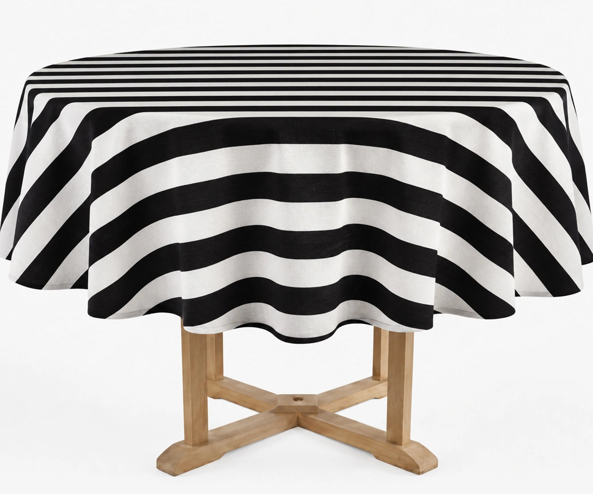 A round table covered with a black and white striped tablecloth, shown on a light wood table against a plain white background.