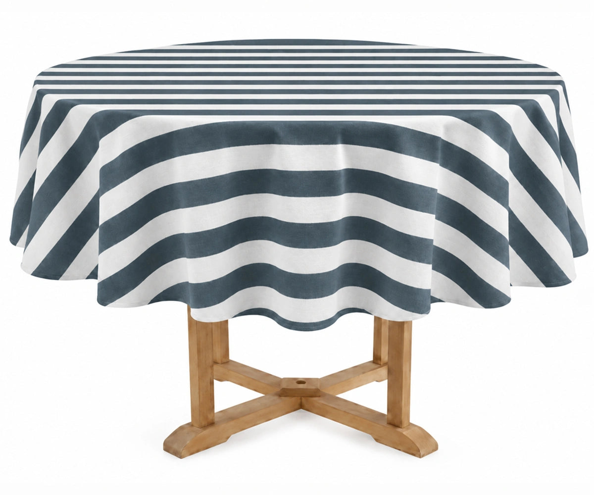 A round table covered with a ocean blue and off-white striped tablecloth, shown on a light wood pedestal table against a plain white background.