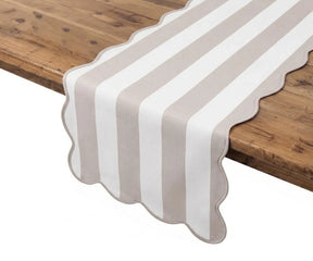 Cabana striped blush and white cotton table runner with scalloped edges displayed on a rustic wooden table.