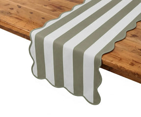 Olive and white cabana striped cotton table runner with scalloped borders on a wooden dining table.