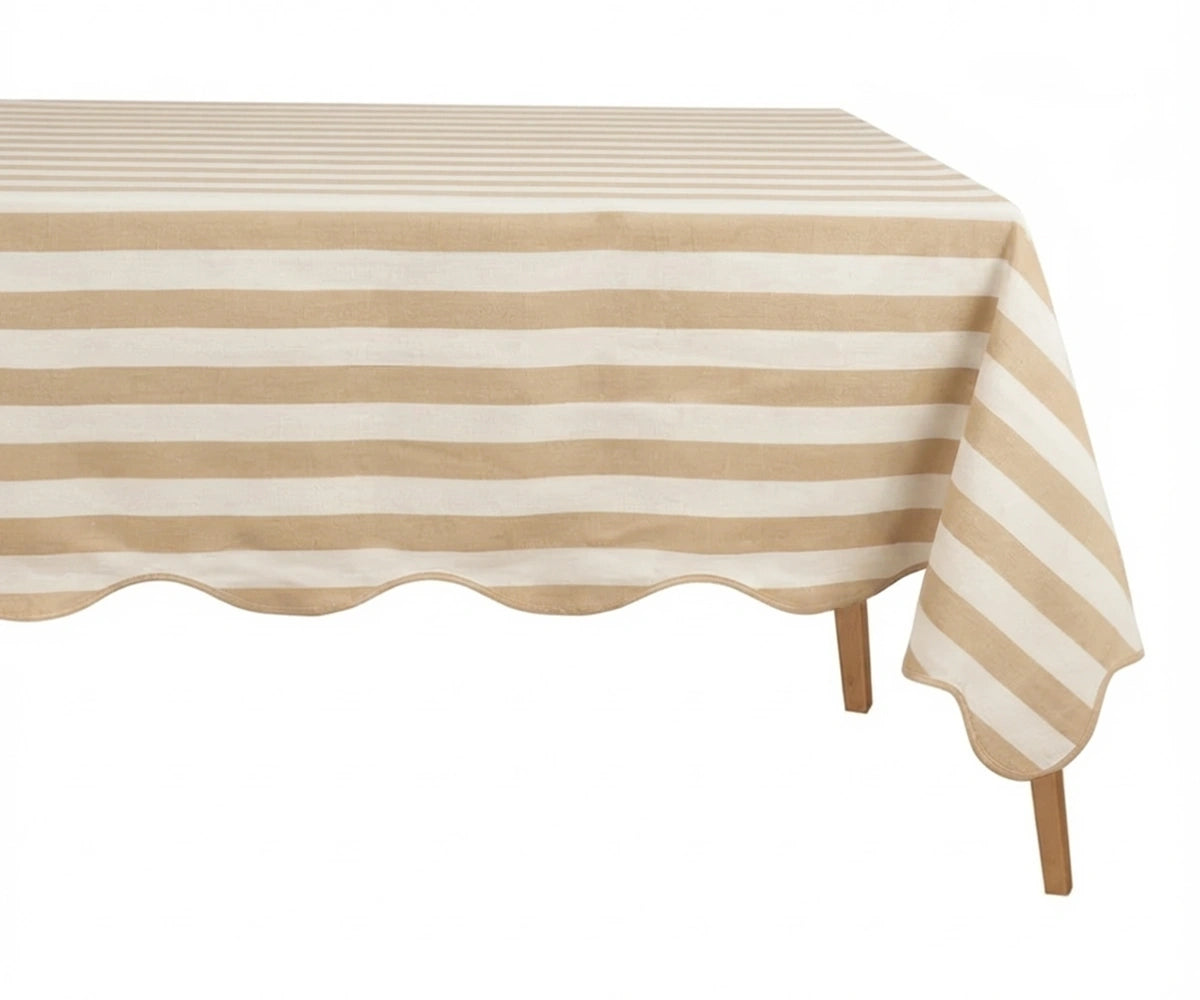 Beige and white cabana striped tablecloth with a scalloped edge on a wooden table.
