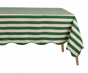 Green and white cabana striped tablecloth with a scalloped edge on a wooden table.