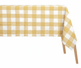 Pale yellow and white checkered cotton tablecloth in classic gingham plaid pattern on rectangular dining table