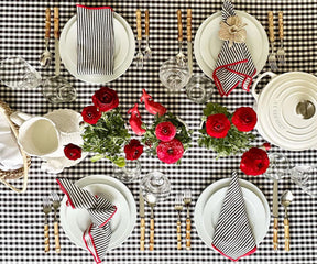 A charming combination of tablecloths graces the table, including a buffalo check, a green plaid, a tablecloth with a plaid pattern, and a timeless black and white plaid, adding flair and character to the setting.