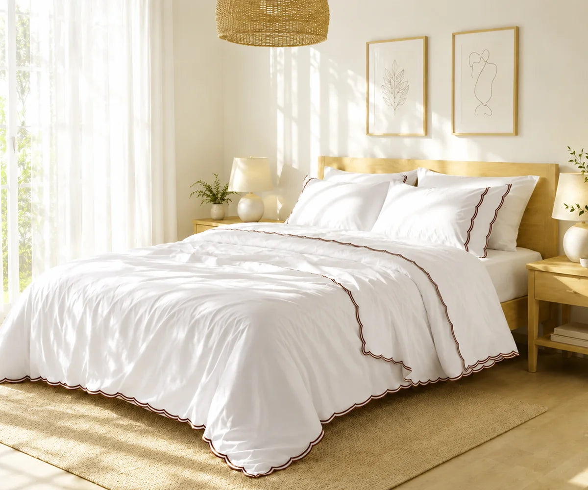  White cotton bedspread set with chocolate brown scalloped edge embroidery styled on a bed in a bright bedroom