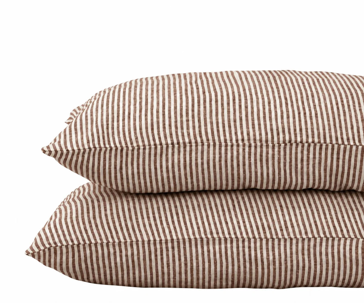 Chocolate brown striped linen pillowcases stacked on a white background