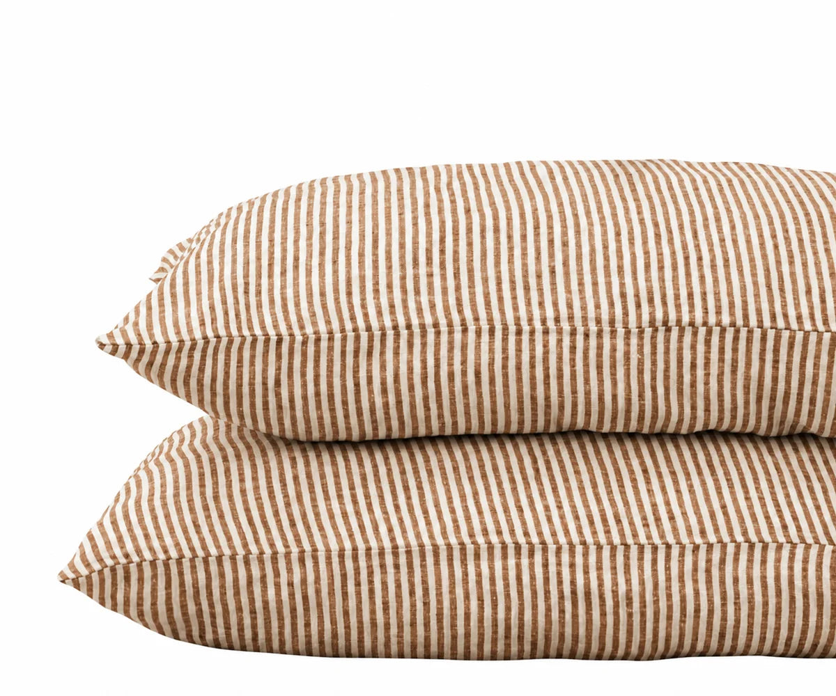 Pair of stacked pillows in coffee brown and white striped linen pillowcases against a plain white background.