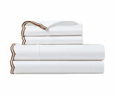 Stacked crisp white bed sheets pillowcases with coffee brown scalloped trim