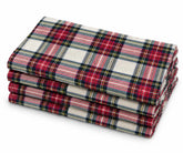 Stacked set of 4 cloth napkins with a classic red, green, and cream tartan plaid pattern