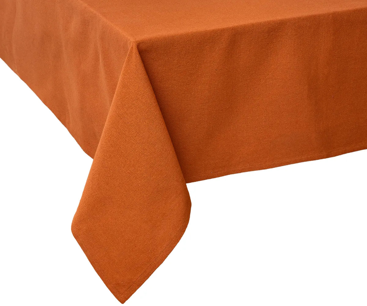 Elegant dining table styled with a coral cotton tablecloth, neutral runners, and floral centerpieces, creating a warm and inviting tablescape for family dinners or weddings.