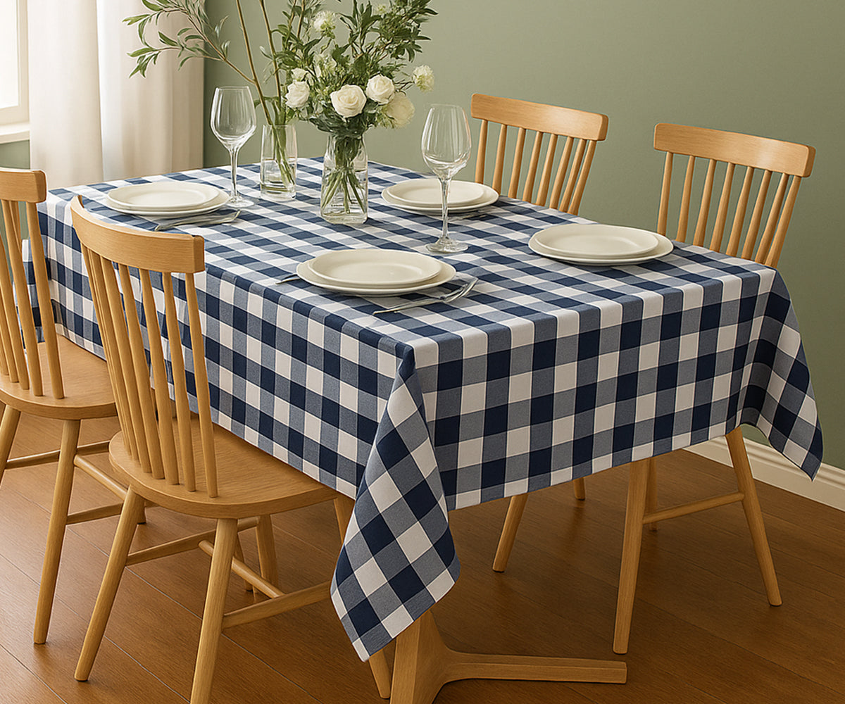 Dining table set with a blue and white checkered tablecloth, plates, glasses, and a vase of flowers.