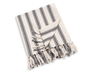 Striped cotton throw blanket used as a decorative layer on a bed or seating area